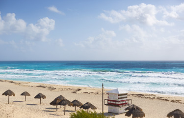 Beach view on the shores of the Caribbean sea. Sunny day. No people in the beach. Umbrellas and turquoise water.