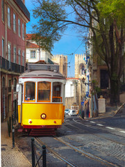 Fototapeta na wymiar Famous vintage yellow 28 tram on street of Alfama, the oldest district of the Old Town, Lisbon, Portugal