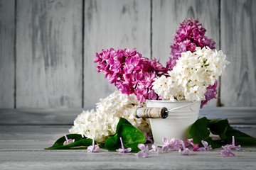 Branches are colored lilac in a basket on the background of wooden boards.