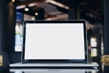 Mockup image of laptop with blank white screen on wooden table in vintage cafe