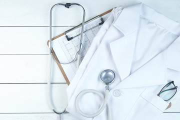 stethoscope,clipboard and doctor’s uniform on white neat wooden desk