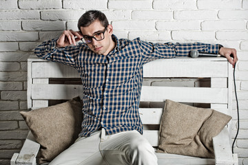man in glasses and checkered shirt on bench with microphone
