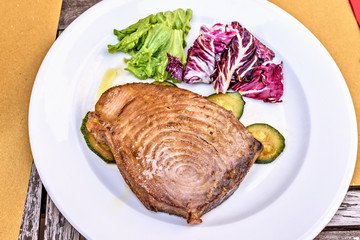 Tuna fish steak with vegetables on a white plate