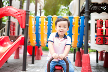 Fototapeta na wymiar Happy asian boy playing seesaw at the playground in the park