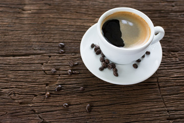 Coffee cup with coffee beans on dark wooden table, black coffee