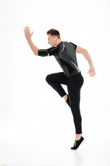 Obraz premium Full length portrait of a young concentrated sportsman in earphones jumps