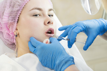 The process of cosmetic surgery of water injection in the area of the lips of a woman 
