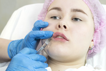 The process of cosmetic surgery of water injection in the area of the lips of a woman 
