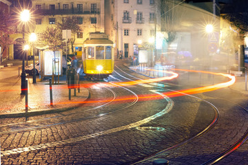 Famous vintage yellow 28 tram of of Alfama, in the oldest district of the Old Town, at night, Lisbon, Portugal - obrazy, fototapety, plakaty