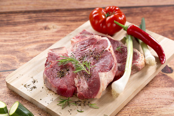 t-bone steak roh auf Holzplatte mit Tomate, Chili, Rosmarien und Zwiebel