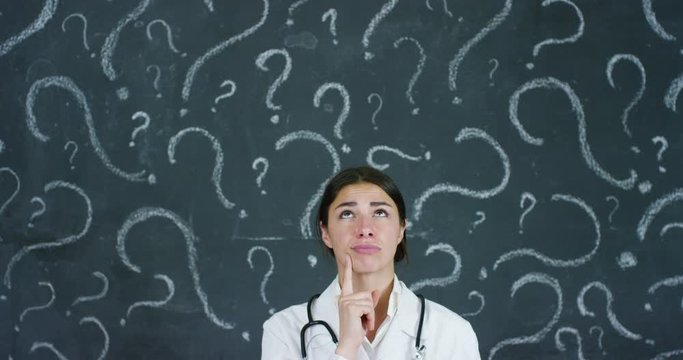 Portrait of a beautiful female doctor (student) thinking about choosing a profession, at a black board. Concept: ideas, school, university, chemistry science teachers memory biology physician question