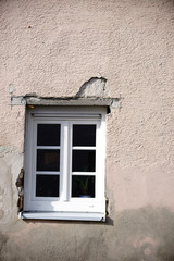 Neu eingesetztes Fenster  / Die Fassade eines renovierungsbedürftigen Hauses mit neu eingesetztem...