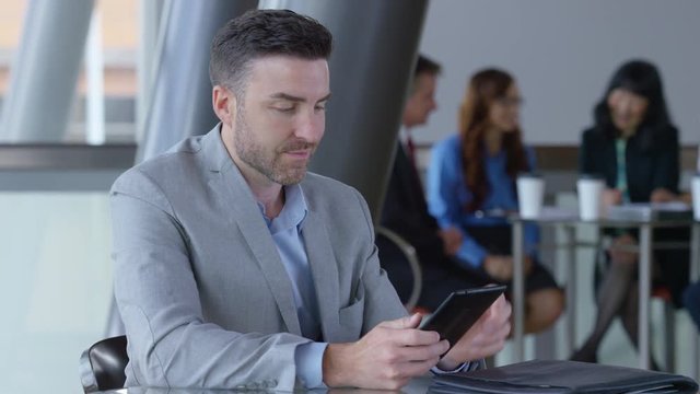 Young businessman using digital tablet in office lobby