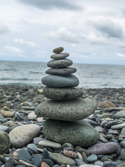 Fototapeta na wymiar Closeup of pile of stones on beach, sea and cloudy sky on background