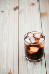 soft drinks. Cola glass with ice cubes on a wood background