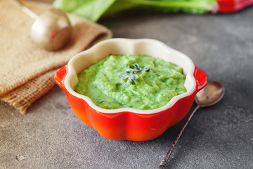 Green cream soup of spinach and broccoli in orange pumpkin bowl