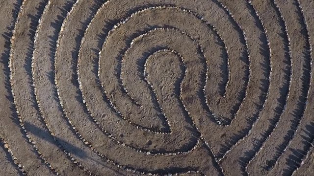 Aerial lift of a woman walking a labyrinth 