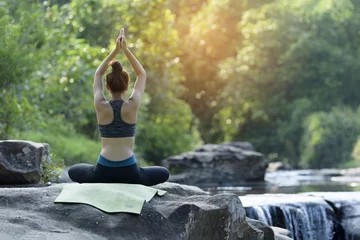 Gordijnen young women practicing yoga in nature near waterfall relax time. © thanatphoto