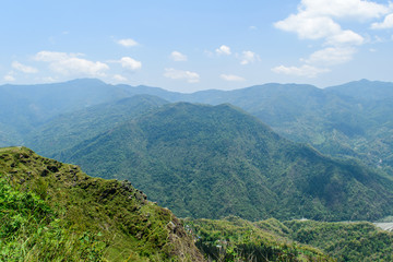 Obraz premium A hilltop view of mountains and blue sky with clouds on a misty day.