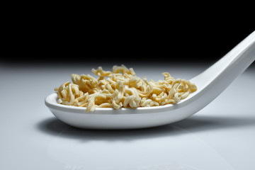 Instant noodles close-up on a white spoon and dark background. (Instant noodles Raw)