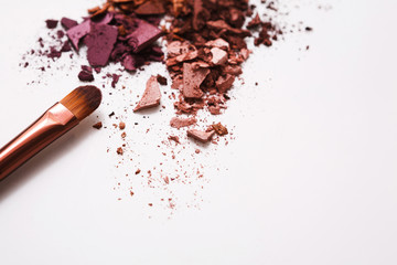 Makeup brushes with blush or eyeshadow of pink, red and coral tones sprinkled on white background