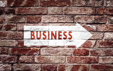 Business arrow sign on aged brick wall background. Conceptual company direction symbol. 