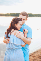 Young couple in love hug each other at the lake outdoor in summer day, harmony concept
