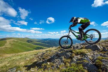 Obraz premium A man is riding bicycle, on the background of mountains and blue sky. Beautiful summer day.