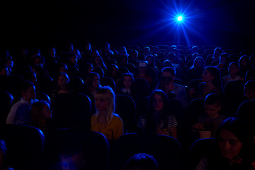 Shot of a dark cinema auditorium full of kids watching a movie together film projector light beam copyspace background layout people children dark interesting entertaining activity lifestyle concept.