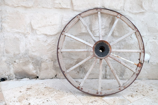 Old wheel of cart leaned on the brick wall