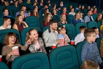 Cinema auditorium full of kids and their parents enjoying premiere of a comedy movie on a weekend happiness positivity leisure emotions excitement amazement entertaining concept.