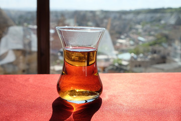 Hot black apple tea in a tulip shaped glass on the red table with city view background