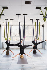Young women doing aerial yoga exercise 