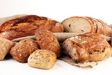 Different kinds of bread and bread rolls on board from above. Kitchen or bakery poster design.