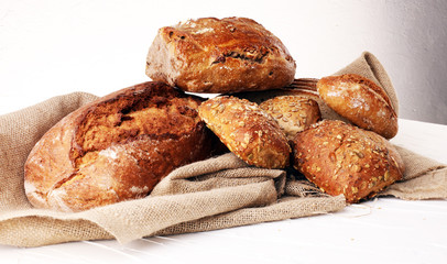 Different kinds of bread and bread rolls on board from above. Kitchen or bakery poster design.