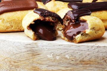 Traditional French dessert. Eclair with chocolate icing. Wooden background