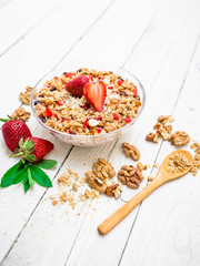 Oatmeal porridge with blueberries, nuts, strawberries and muesli on white wood background. Top view. Diet breakfast.