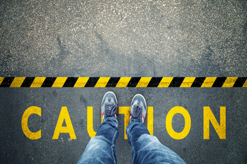 Top view of a man stands on industrial striped asphalt floor with warning yellow black caution...