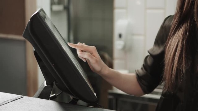 Woman waiter swiping credit card through the computer terminal in cafe and choose