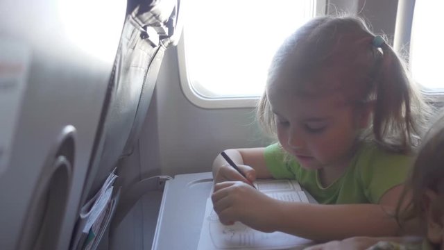 Little girl child draws,  sitting on inside airplane.