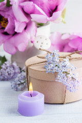 Fototapeta na wymiar Lit candle, peonies and lilac flowers