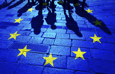 Shadows group of people walking on sunny stone tiled street floor painted with European Union flag. - Powered by Adobe