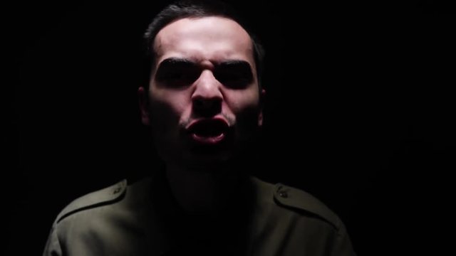Frustrated military man in darkness screaming at the camera.