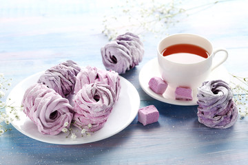 Fototapeta na wymiar Sweet zephyr with cup of tea on blue wooden table