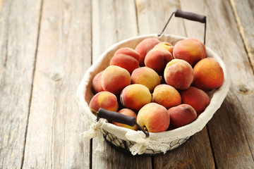 Sweet peach fruit in basket on grey wooden table