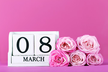 Beautiful pink roses with cube calendar on pink background