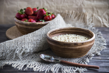 Oatmeal with linseed and strawberries in clay dishes