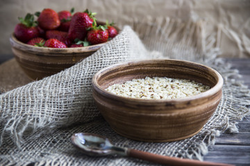 Oatmeal with linseed and strawberries in clay dishes