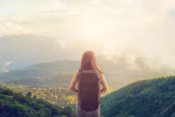 Tourist traveler concept, Young hipster girl with backpack enjoying sunset on peak mountain