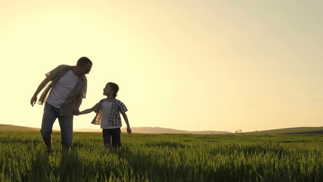 Father and son walking on the field at the day time. People having fun outdoors. Concept of friendly family.